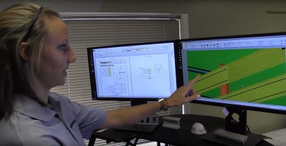 A young woman points to a detailed rendering on a computer screen.