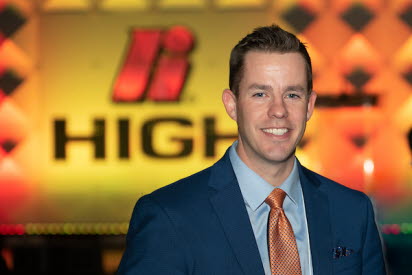 John McCormick stands in front of the stage at the High Forum with a giant High logo in the background.