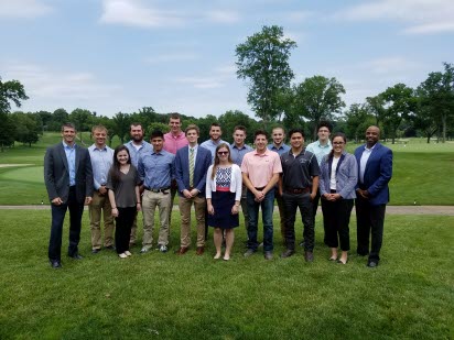 A group of students with High executives smiles for the camera.